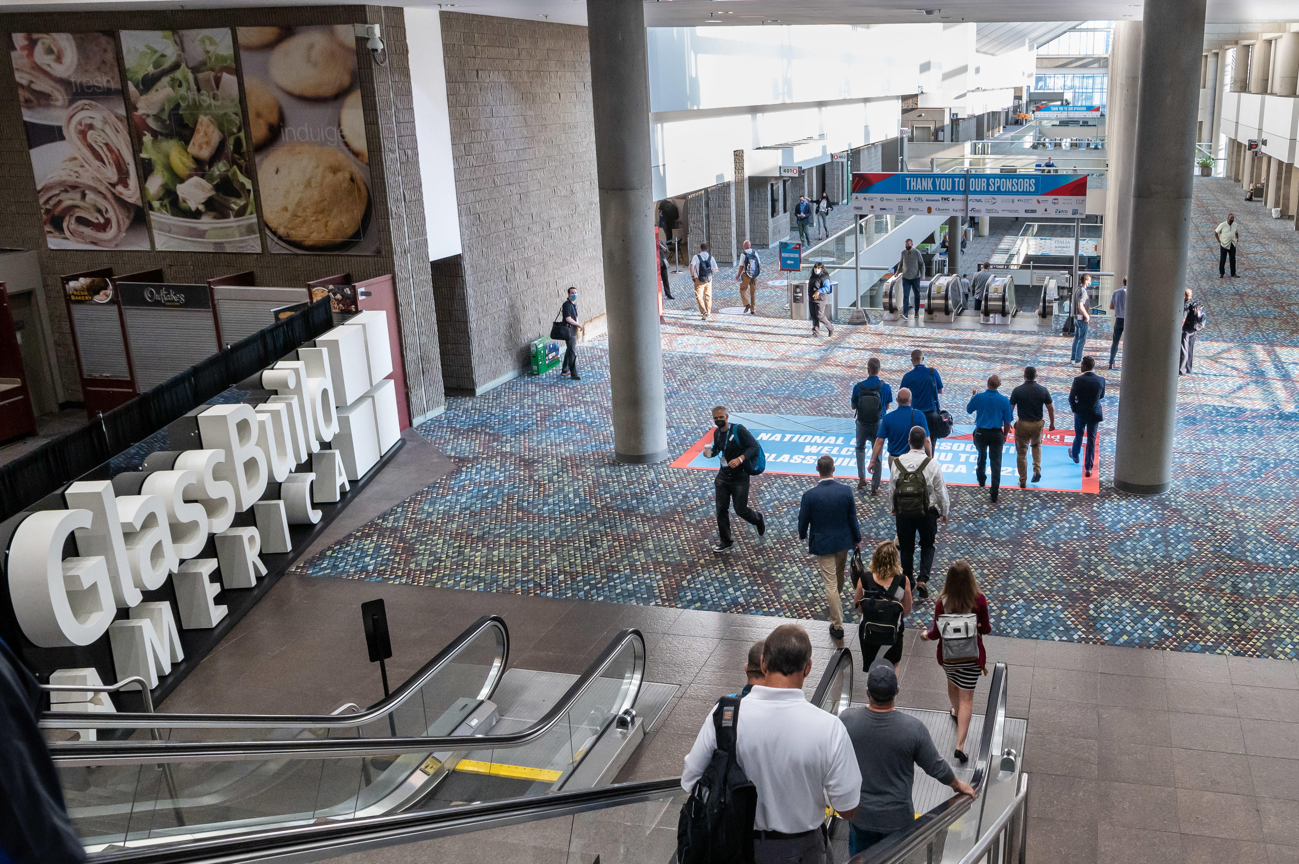 GlassBuild 2021 attendees enter Hall C on an escalator